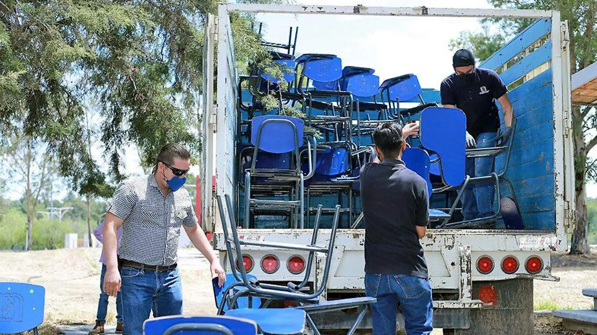 personas descargan pupuitres de camioneta